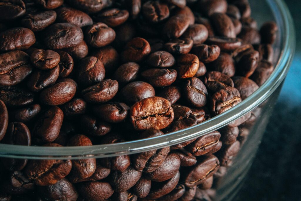 A detailed close-up of roasted coffee beans inside a clear glass bowl for a rich aroma experience.